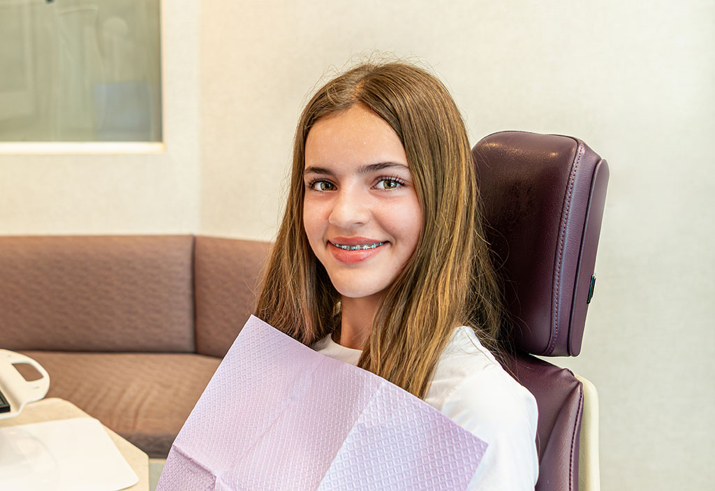 A smiling teenager shows off their new braces, a popular choice at Kelleher Orthodontics.