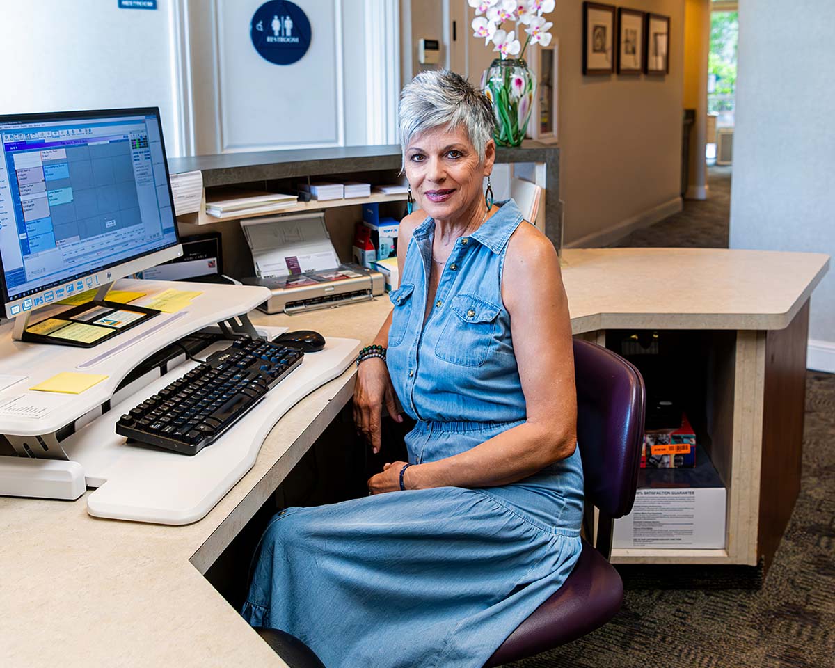 Friendly orthodontics staff smiling at the front desk; a sign of a welcoming and safe environment for patients.