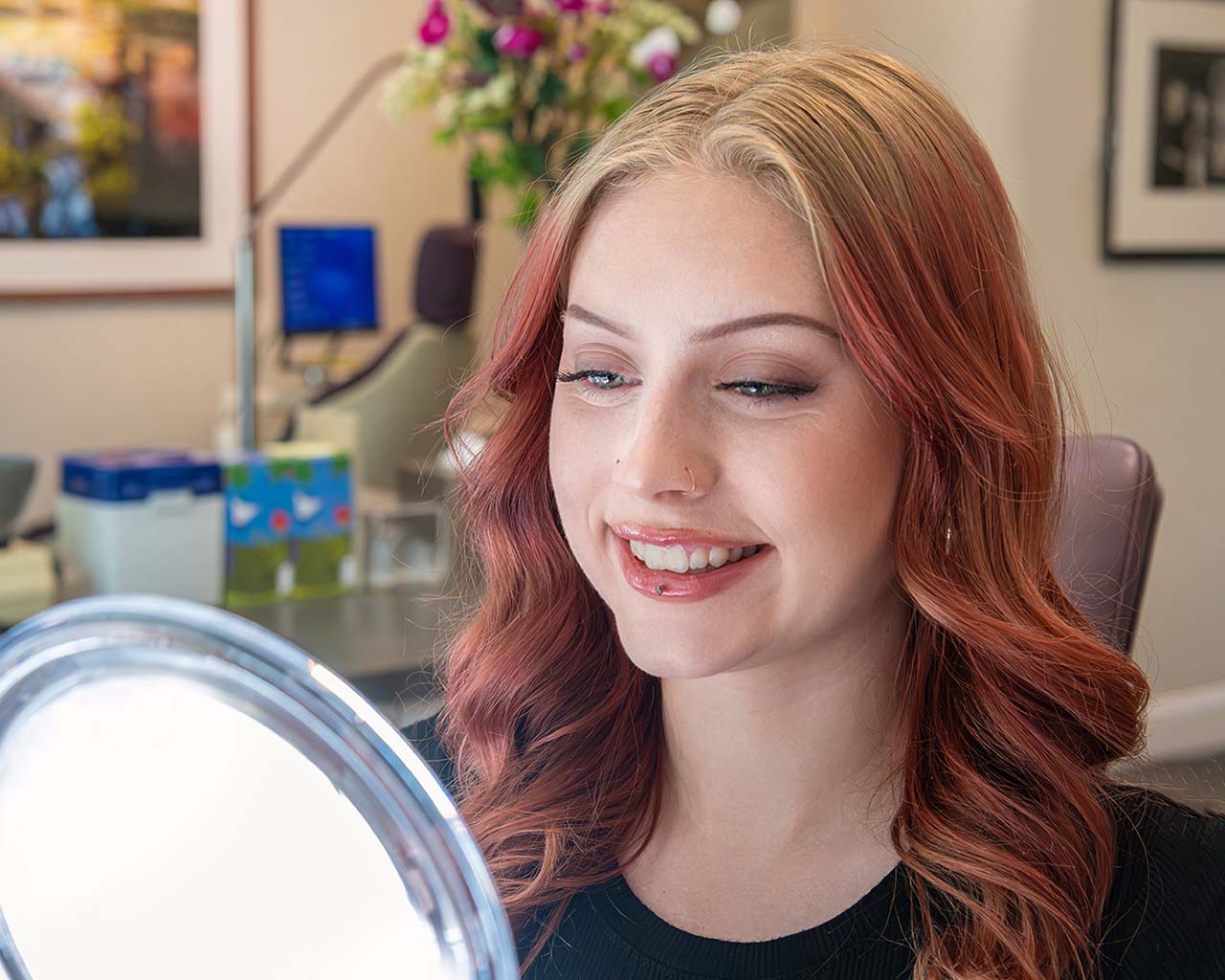 Happy patient with a bright smile looking in the mirror during an orthodontic appointment.