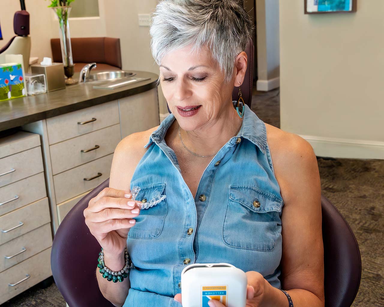 Senior woman happily examining her new clear Invisalign aligner trays.