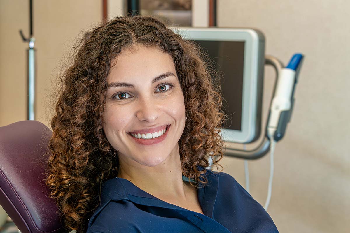 A smiling woman feels relief after a successful TMJ treatment at Kelleher Orthodontics.
