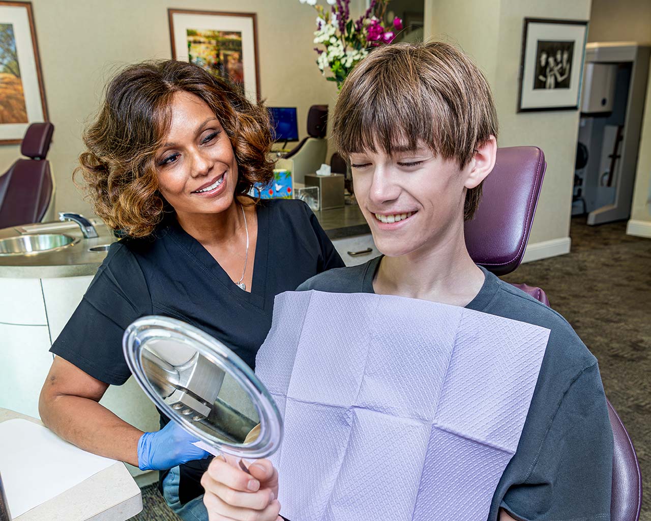 Teenage orthodontics patient smiling at his reflection, confident with his new braces.
